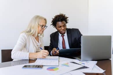 Elderly Woman Looking at her customer journey on a Computer Beside a Man in Black Suit