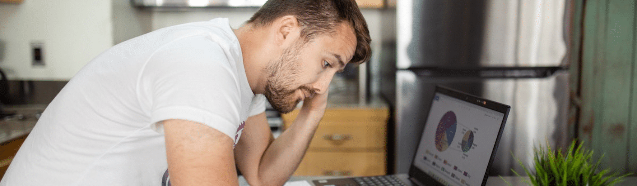 Man in White T-shirt Using Laptop Computer looking at data