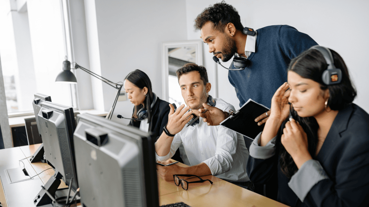 Support team in headsets reviewing Fin AI agent conversations with a supervisor during an Intercom implementation