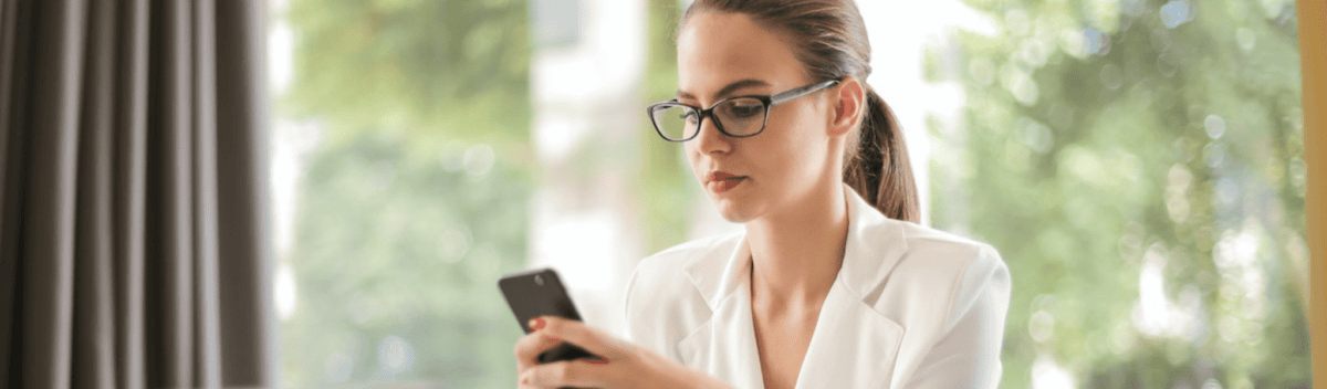 Serious businesswoman using smartphone in workplace