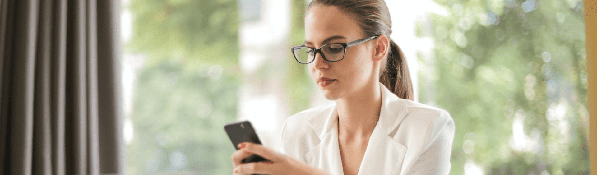 Serious businesswoman using smartphone in workplace