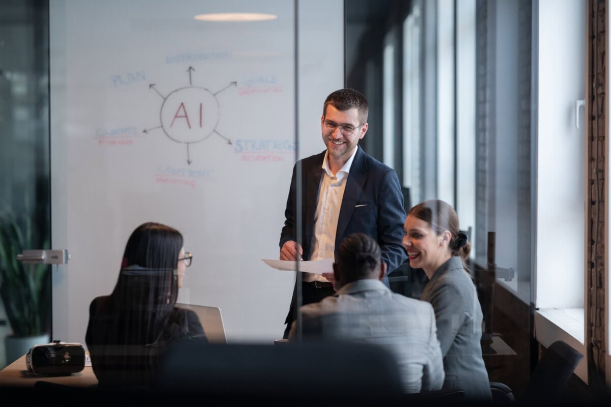 Customer service leaders discussing AI strategy in a meeting with an AI workflow diagram on a whiteboard.