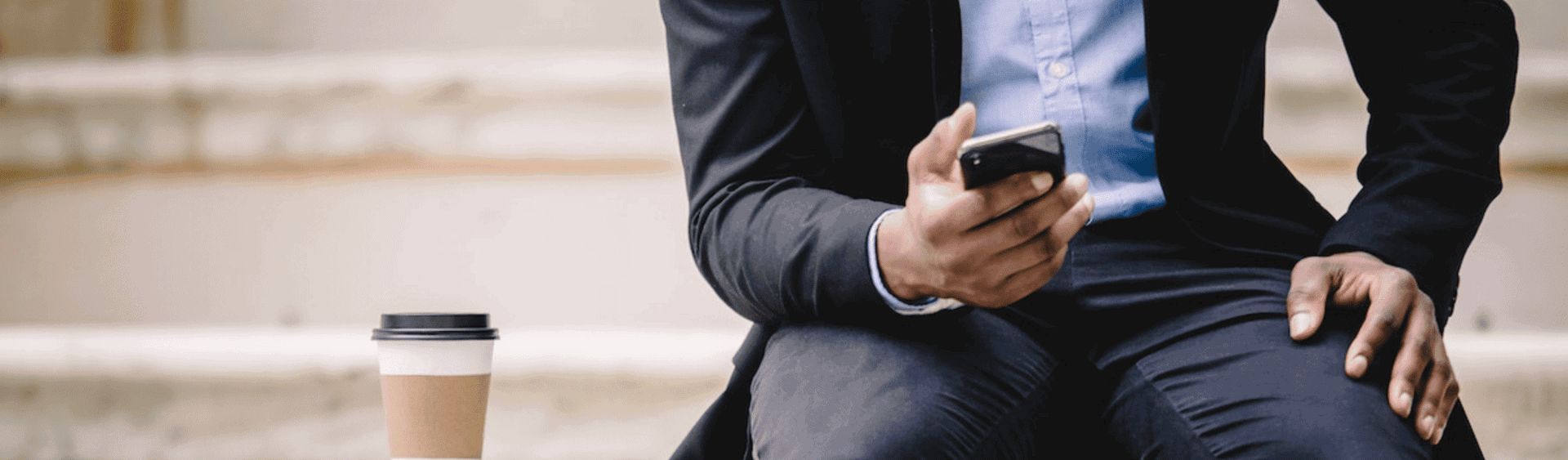 Crop businessman using sms smartphone while resting on bench with takeaway coffee