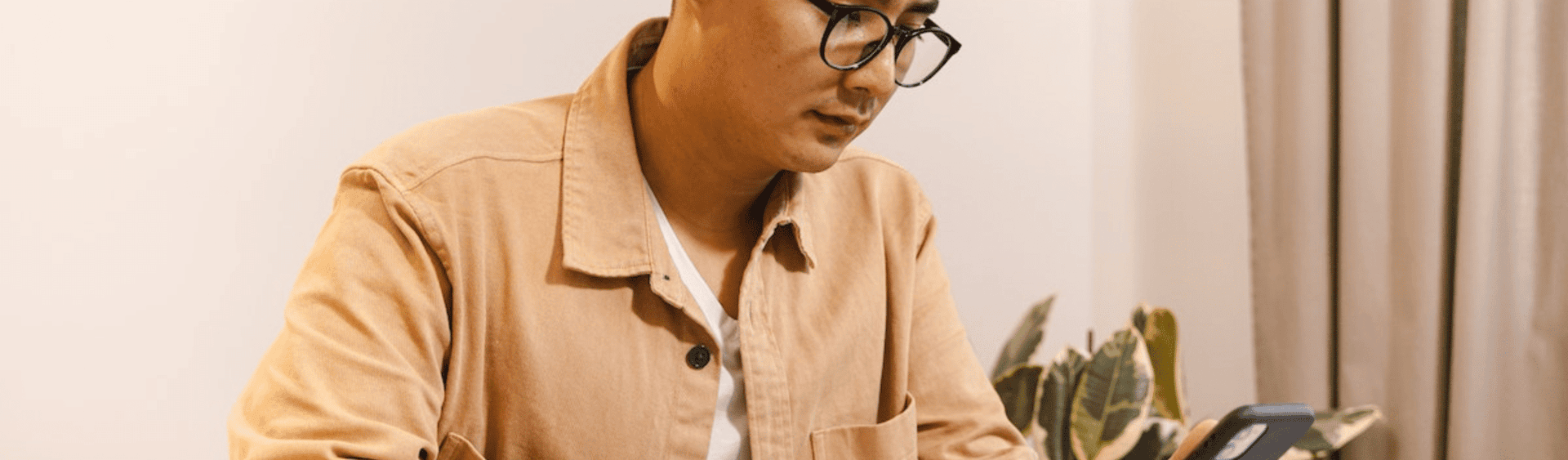Man Sitting at a Table with a Smart Phone and Notebook