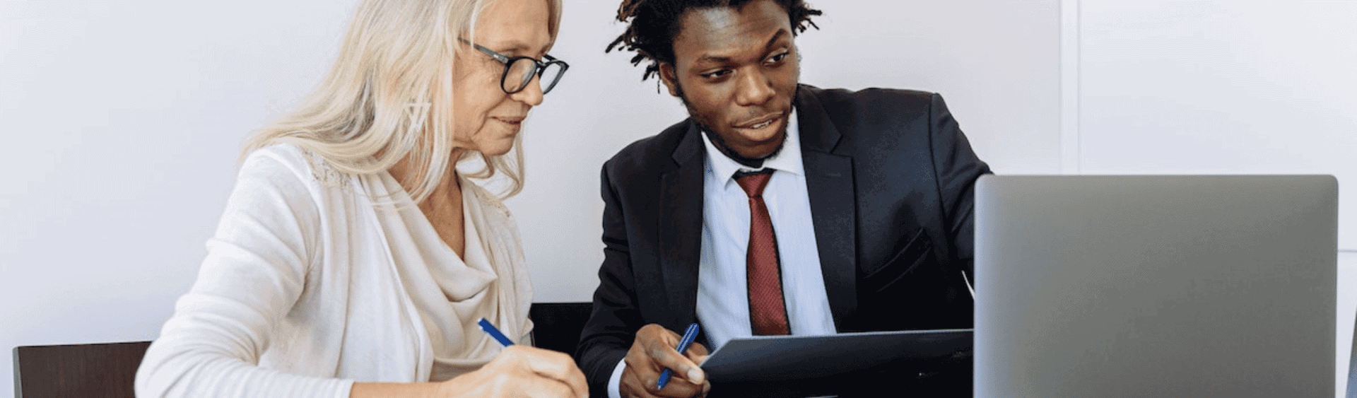 Elderly Woman Looking at her customer journey on a Computer Beside a Man in Black Suit